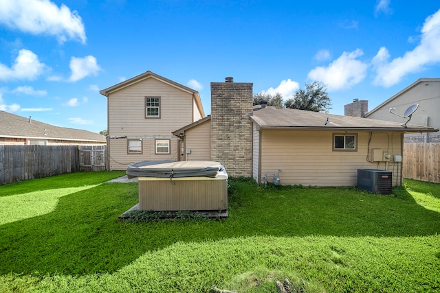 back of house with a hot tub, a yard, and central AC