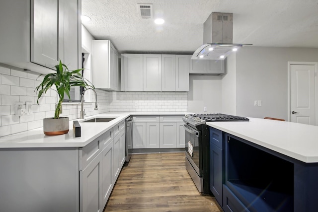 kitchen with sink, dark hardwood / wood-style floors, a textured ceiling, island range hood, and stainless steel appliances