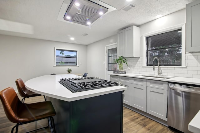 kitchen with sink, a center island, stainless steel appliances, a breakfast bar area, and gray cabinets