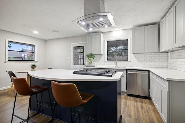 kitchen with appliances with stainless steel finishes, sink, wood-type flooring, a kitchen island, and a breakfast bar area