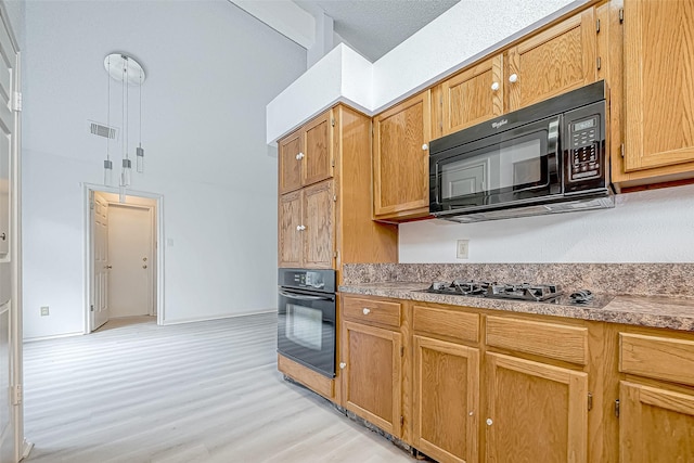 kitchen featuring light countertops, light wood-type flooring, visible vents, and black appliances