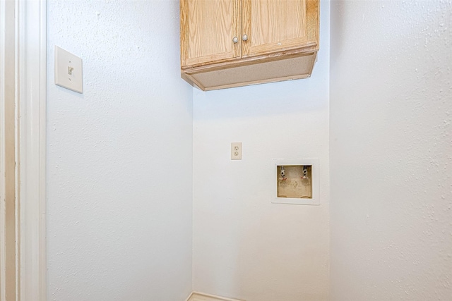 clothes washing area featuring hookup for a washing machine and cabinet space