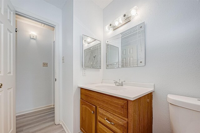 bathroom featuring toilet, wood finished floors, vanity, and baseboards