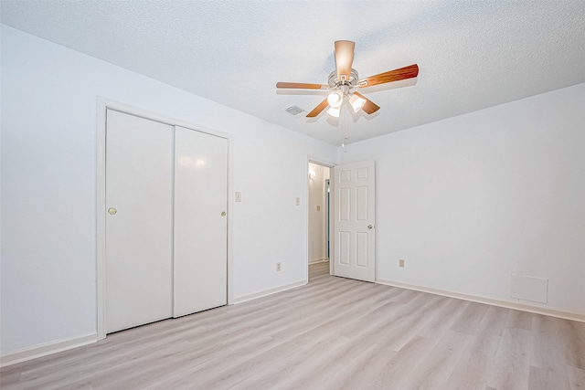 unfurnished bedroom featuring light wood-style floors, visible vents, a textured ceiling, and baseboards