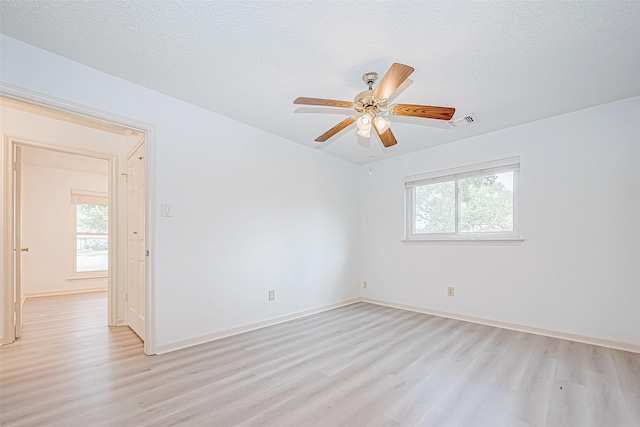 spare room with a textured ceiling, visible vents, and light wood-style floors