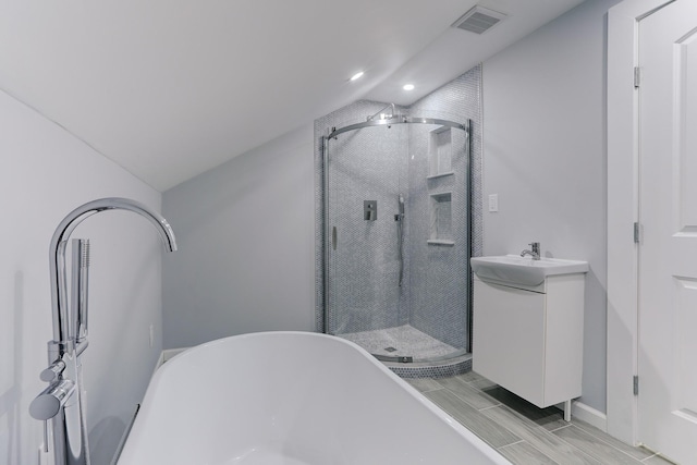 bathroom with vanity, wood-type flooring, plus walk in shower, and vaulted ceiling