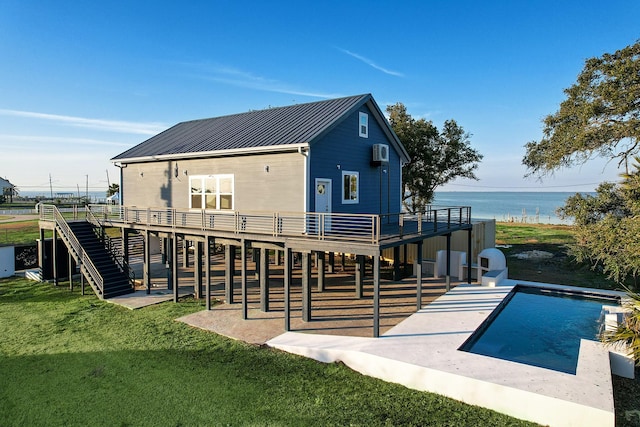 back of property featuring a swimming pool side deck with water view, a yard, and a patio