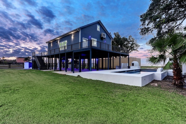 back house at dusk featuring a wall mounted AC and a lawn