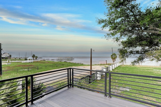 deck with a lawn and a water view