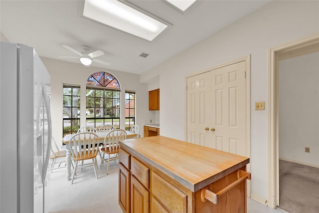 interior space with white refrigerator, light colored carpet, a kitchen island, and ceiling fan