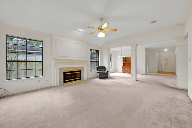 unfurnished living room featuring ornate columns, light carpet, ceiling fan with notable chandelier, and ornamental molding