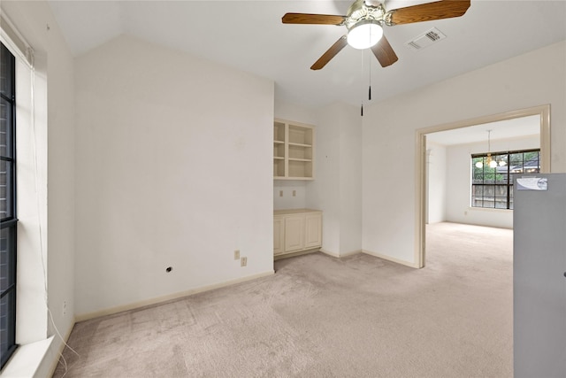 carpeted empty room featuring ceiling fan with notable chandelier and lofted ceiling