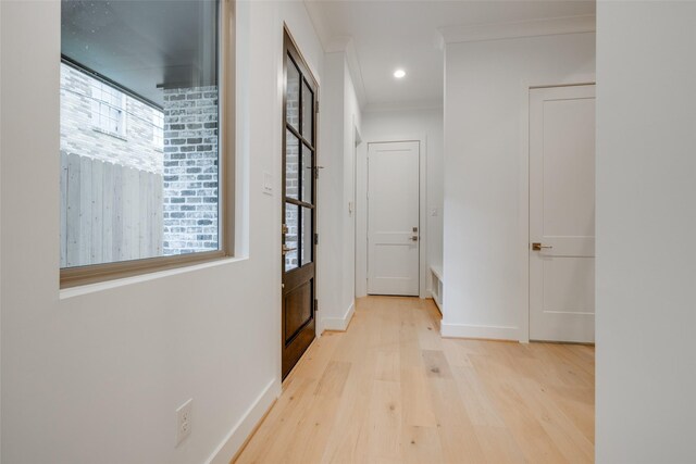 corridor with ornamental molding and light wood-type flooring