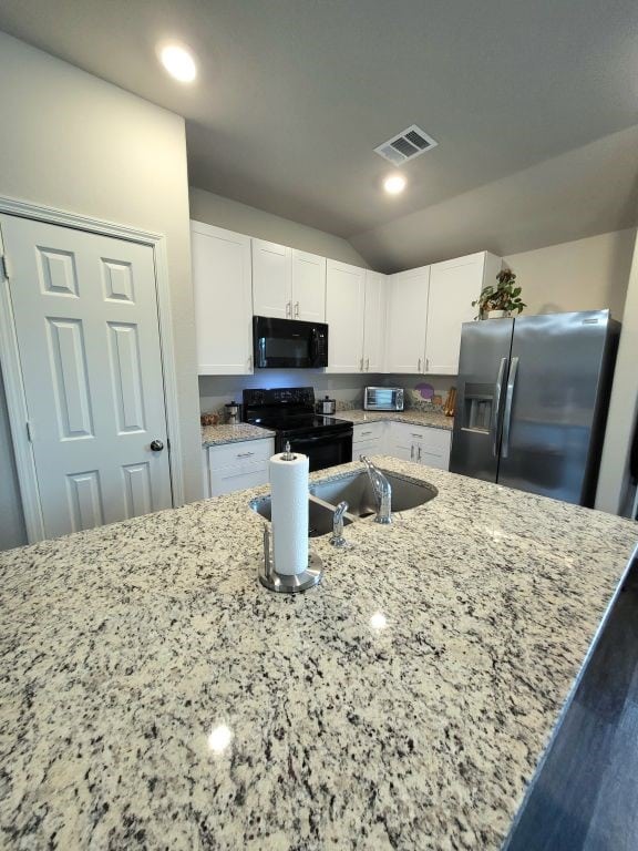 kitchen featuring lofted ceiling, black appliances, white cabinets, dark hardwood / wood-style floors, and light stone countertops