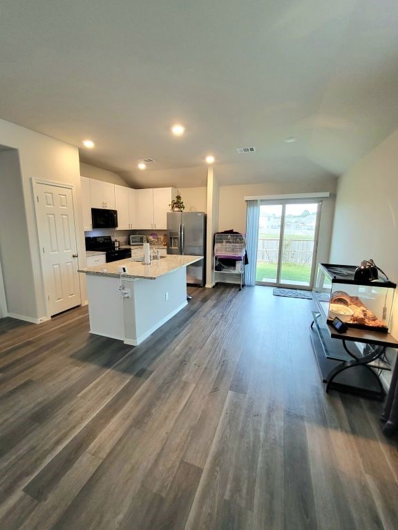 kitchen with white cabinetry, dark hardwood / wood-style flooring, an island with sink, a breakfast bar area, and black appliances