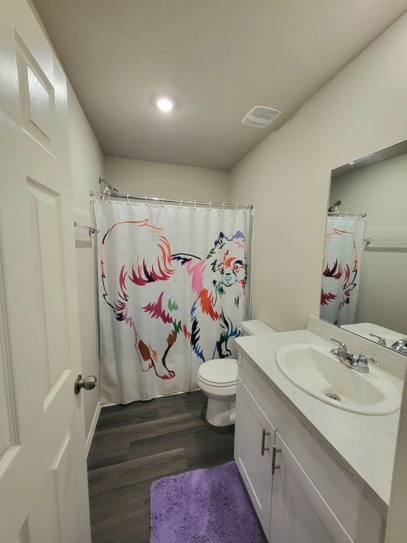 bathroom featuring hardwood / wood-style floors, vanity, toilet, and walk in shower