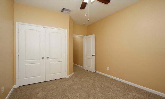 unfurnished bedroom with ceiling fan, light carpet, and a closet