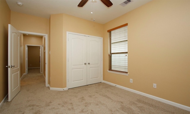 unfurnished bedroom with a closet, light colored carpet, and ceiling fan