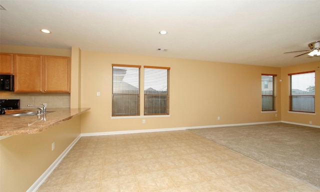 interior space with black appliances, light colored carpet, sink, and a wealth of natural light