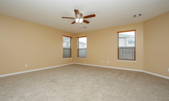 carpeted empty room with ceiling fan and a healthy amount of sunlight