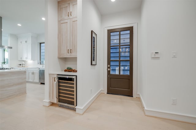 entryway with wine cooler, recessed lighting, light wood-style floors, and baseboards