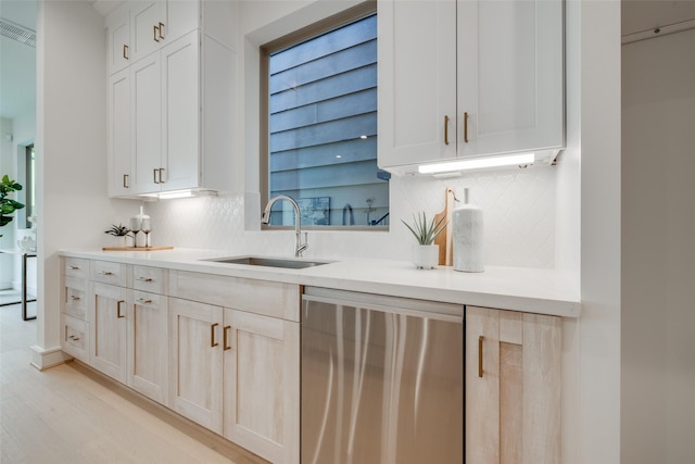 kitchen featuring stainless steel dishwasher, light countertops, tasteful backsplash, and a sink