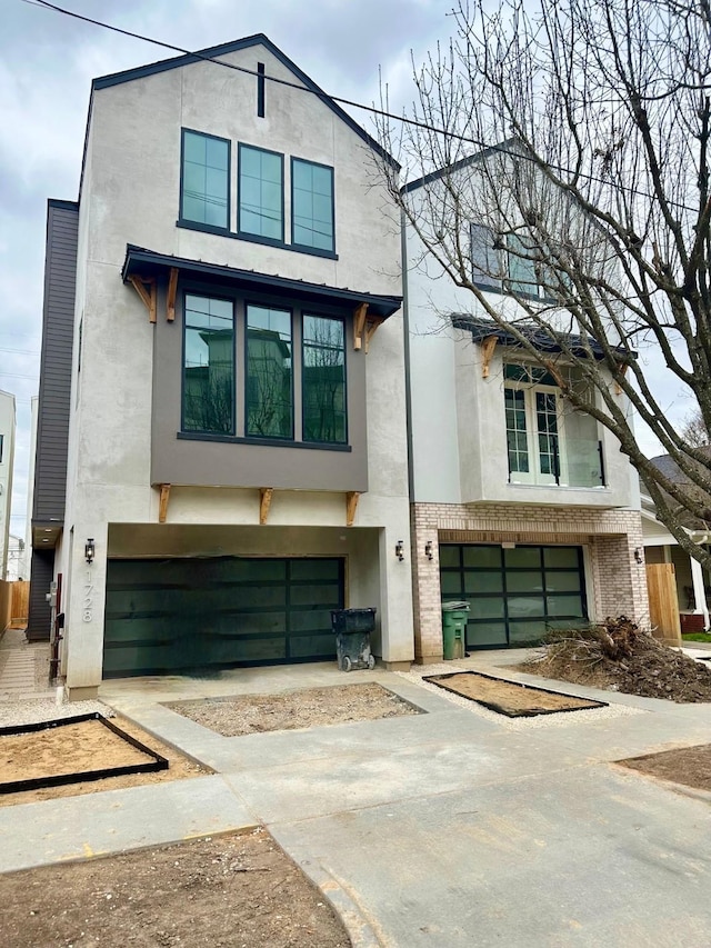 contemporary house featuring an attached garage, brick siding, driveway, and stucco siding