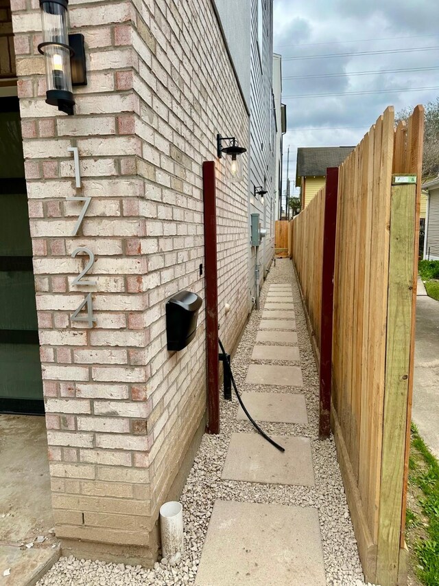 view of home's exterior featuring brick siding and fence