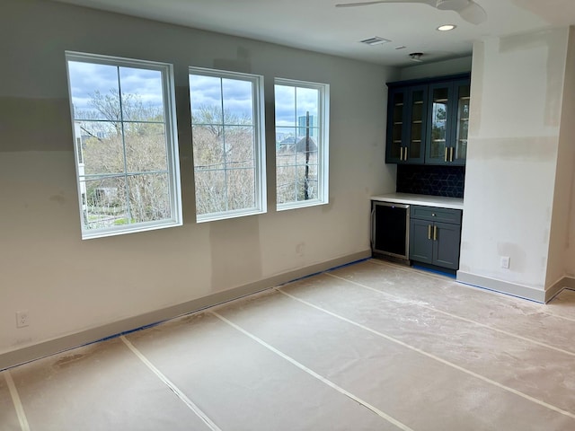 bar featuring visible vents, concrete floors, baseboards, and decorative backsplash