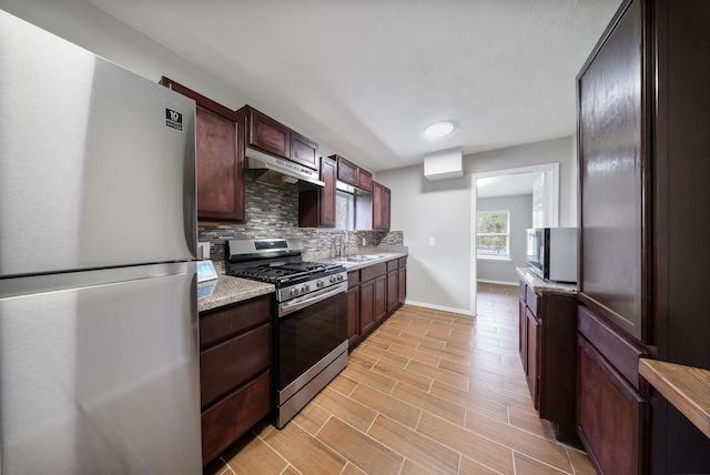 kitchen with tasteful backsplash, light stone countertops, sink, and appliances with stainless steel finishes