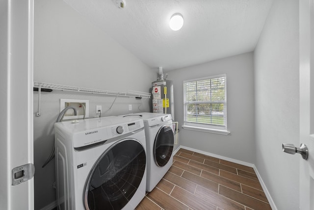 laundry room with a textured ceiling, washer and clothes dryer, dark wood-type flooring, and gas water heater