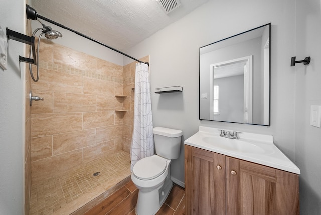 bathroom featuring a shower with curtain, wood-type flooring, a textured ceiling, toilet, and vanity