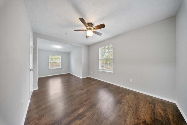 empty room with ceiling fan, dark wood-type flooring, and a textured ceiling