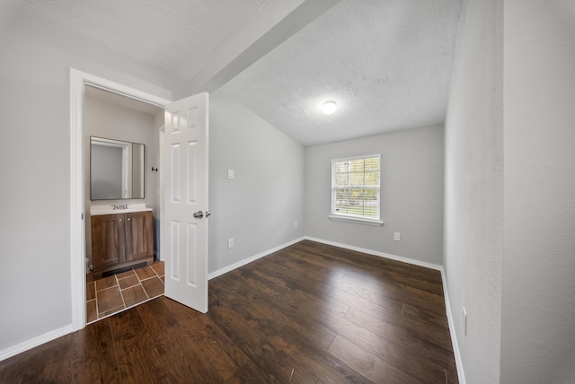 spare room featuring dark hardwood / wood-style flooring and a textured ceiling