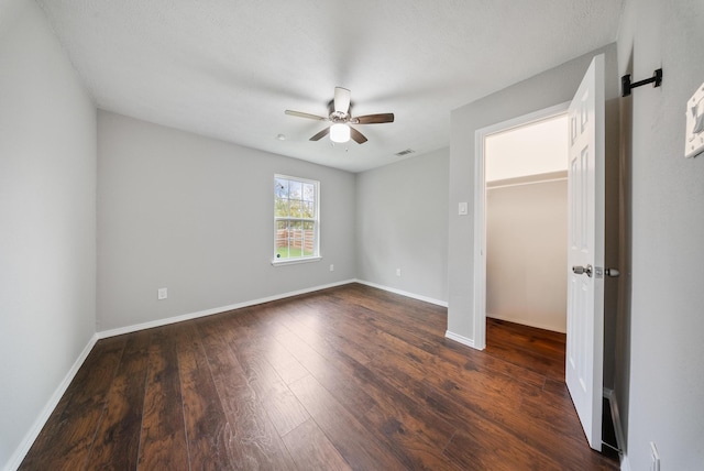 unfurnished bedroom with ceiling fan and dark wood-type flooring