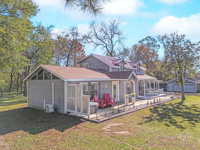 rear view of house featuring a patio area, an outbuilding, a garage, and a lawn