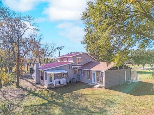 rear view of house featuring roof with shingles, central AC unit, and a lawn