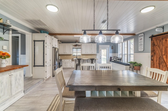 dining room featuring wood ceiling, visible vents, and a barn door