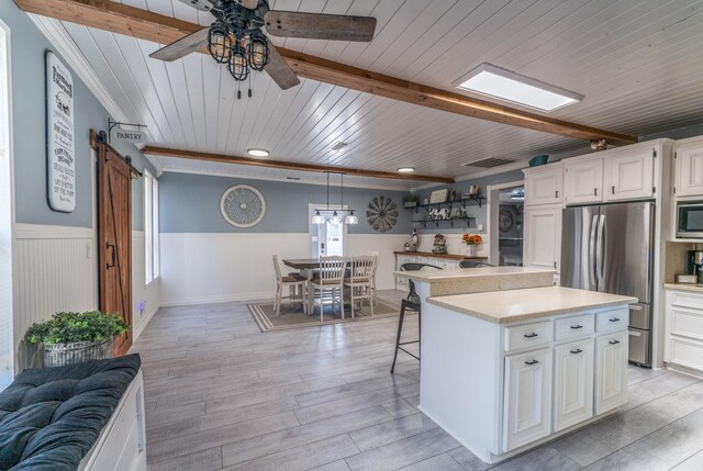 kitchen with a kitchen island, decorative light fixtures, white cabinetry, stainless steel appliances, and a barn door