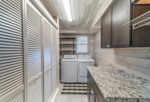 laundry area with wood walls, wood ceiling, light wood-style floors, independent washer and dryer, and cabinet space