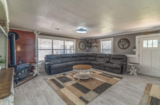 living area with ornamental molding, plenty of natural light, wood finished floors, and visible vents