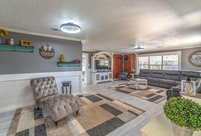 living area featuring a wood stove, visible vents, crown molding, and wood finished floors