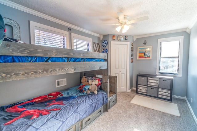 bedroom with a textured ceiling, carpet floors, visible vents, baseboards, and crown molding