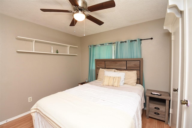 bedroom with ceiling fan, a textured ceiling, and light wood-type flooring