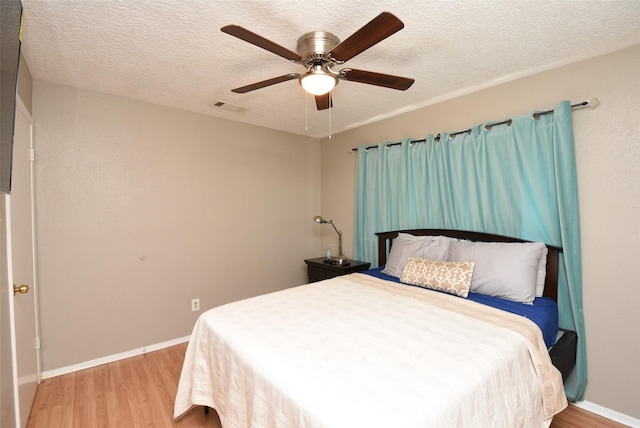 bedroom with ceiling fan, a textured ceiling, and light wood-type flooring