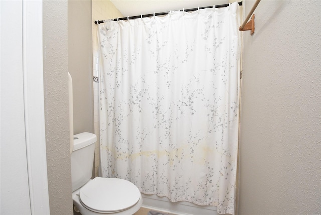 bathroom featuring a shower with shower curtain and toilet