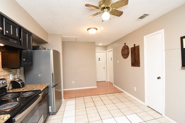 kitchen with light stone countertops, stainless steel electric range oven, backsplash, and light hardwood / wood-style flooring