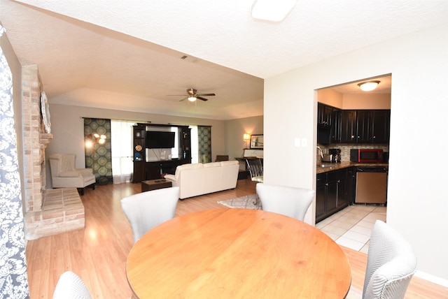 dining room with ceiling fan, sink, light wood-type flooring, and a textured ceiling