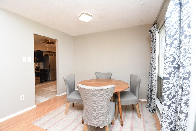 dining space with light hardwood / wood-style flooring and a textured ceiling