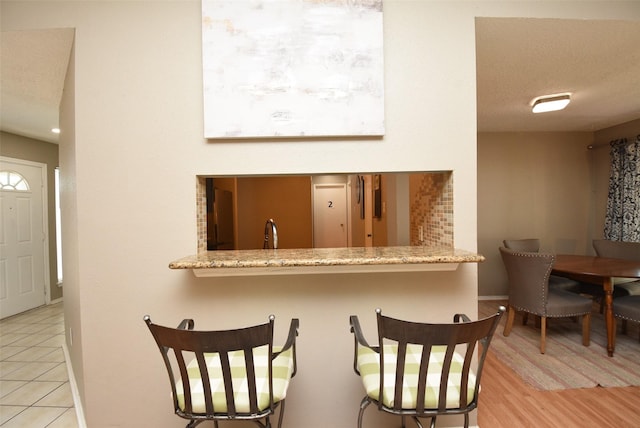 kitchen featuring a textured ceiling, light hardwood / wood-style floors, and light stone counters